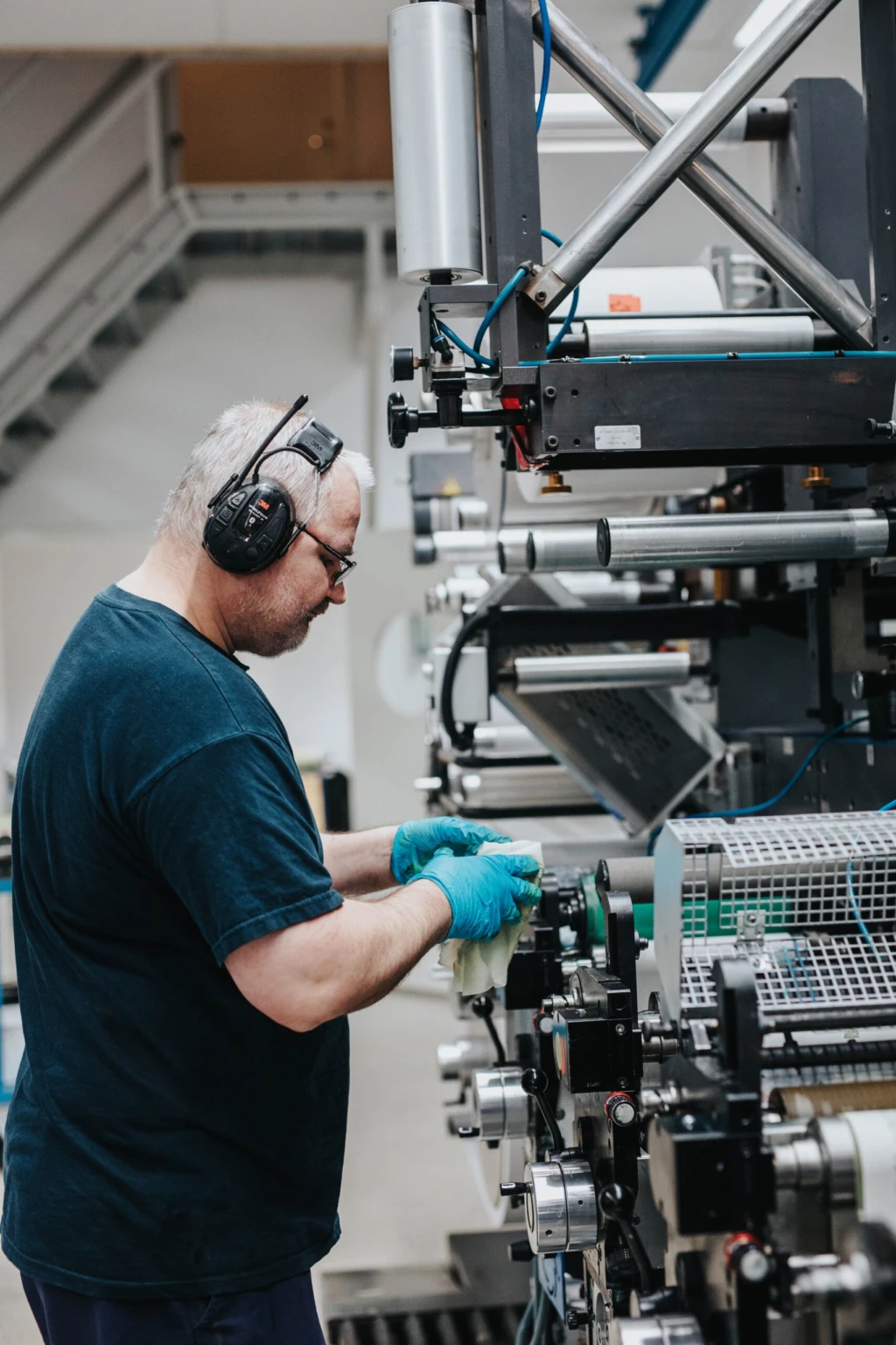 Man med hörselkåpor arbetar vid en industriell maskin.