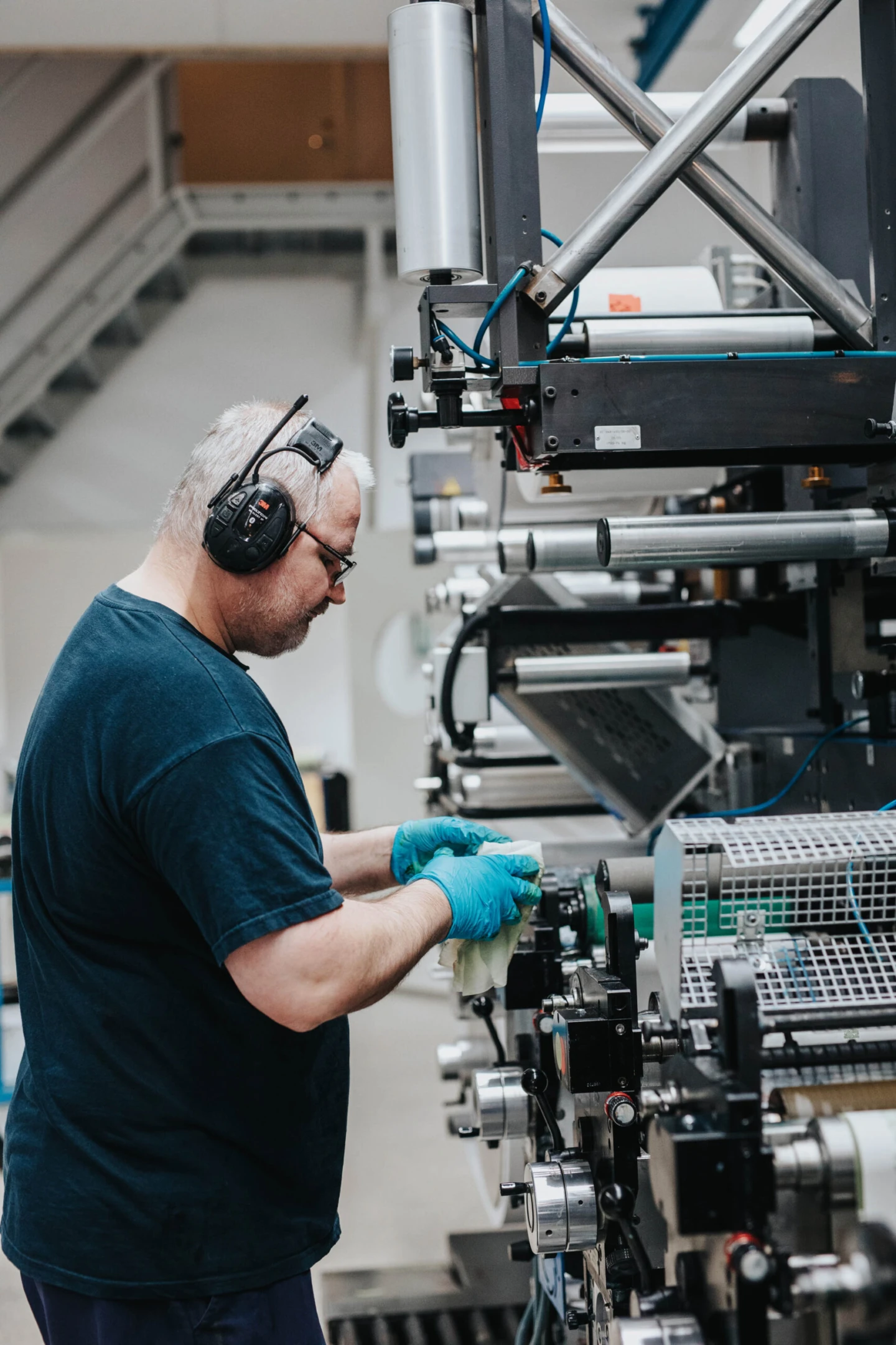 Man med hörselkåpor arbetar vid en industriell maskin.