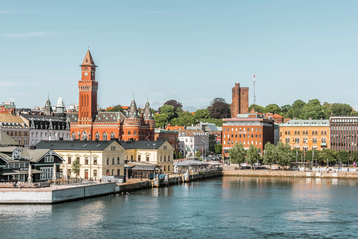 Stad vid vattnet med rött torn och äldre byggnader.