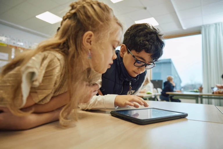 Barn samarbetar vid surfplatta.