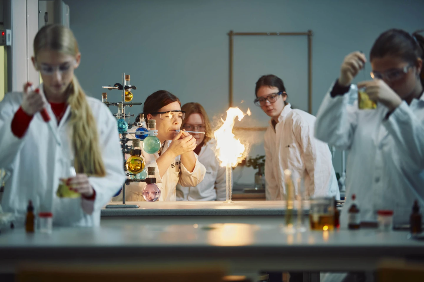 Elever i labbrockar gör ett kemiexperiment.