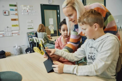 Lärare hjälper barn med surfplatta.