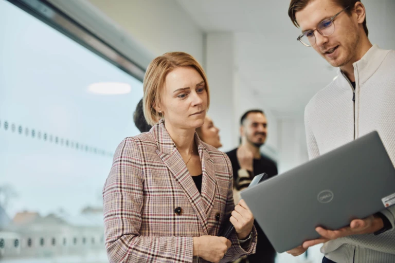 Två kollegor tittar på en laptop tillsammans.