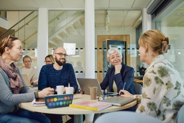 Fyra personer har möte runt ett bord i ett modernt kontor.
