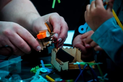 Händer som bygger en liten teknisk konstruktion med komponenter.