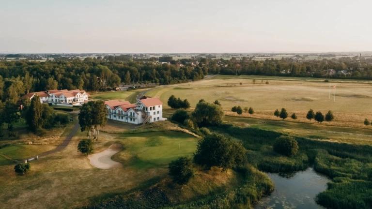 En flygbild över Lydinge Resort i Åstorp, omgivet av golfbanor och grön natur – en lugn oas för avkoppling och sport.
