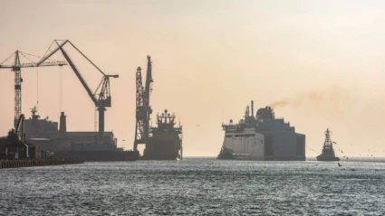 Skeppsvarvet i Landskrona syns i varmt kvällsljus med stora kranar och fartyg som lastas i hamninloppet.