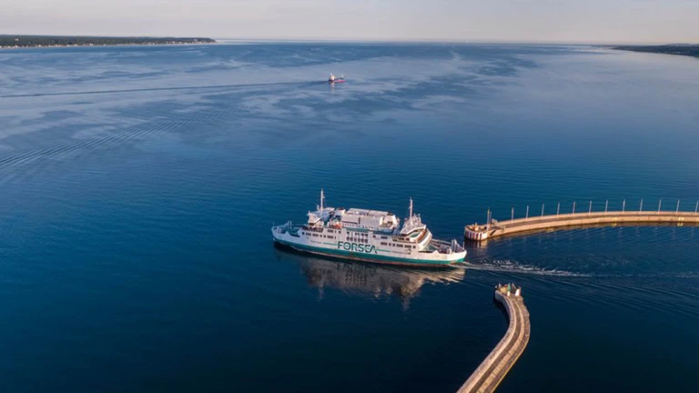 En vit ForSea-färja färdas lugnt ut från hamninloppet över det spegelblanka vattnet i Öresund.