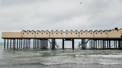Det klassiska kallbadhuset i Helsingborg sträcker sig ut över vågorna med sina gula träbyggnader på höga pelare.
