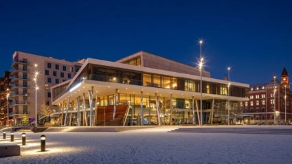 Det moderna konferenshotellet i Helsingborg lyser upp mot den blå kvällshimlen, omgivet av stadens historiska byggnader.