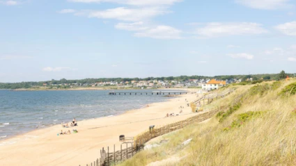 Den långa sandstranden vid Klitterhus kantas av dynor och havsutsikt, med badande och solande besökare.