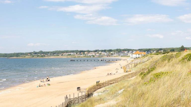 Den långa sandstranden vid Klitterhus kantas av dynor och havsutsikt, med badande och solande besökare.
