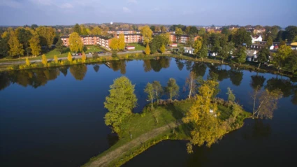 En stilla sjö speglar höstfärgade träd och byggnader vid Ljungkullen, ett naturnära område med rofylld atmosfär.