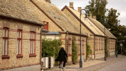 En stillsam gata i Ängelholm med charmiga tegelhus och kullersten, där en cyklist passerar i höstljus.