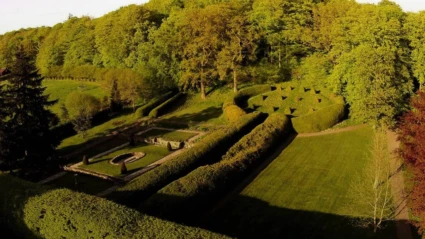 Den vackert anlagda trädgården vid Vrams Gunnarstorps gods breder ut sig med formklippta häckar, gångar och välvårdade gräsmattor i grönskande omgivning.