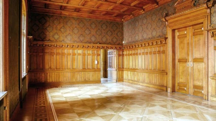 Ett elegant rum i Tranchellska huset med rikt snidade träpaneler, mönstrade tapeter och ett vackert parkettgolv i klassisk stil.
