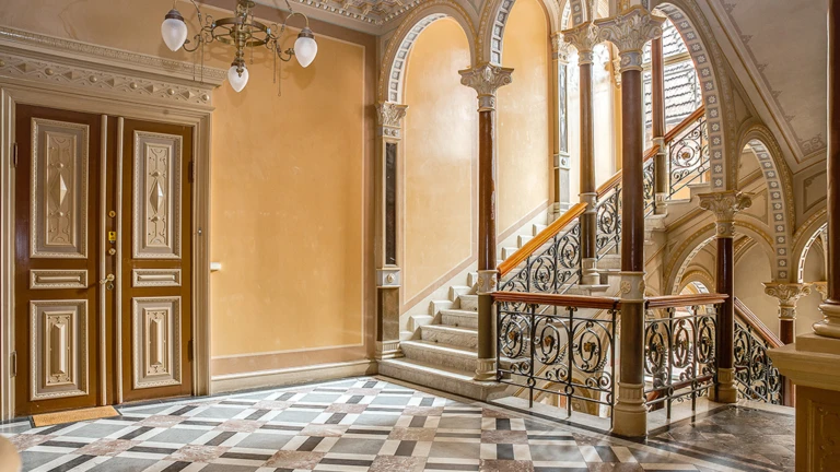 Det praktfulla trapphuset i Tranchellska huset med marmorgolv, pelare och räcken i smidesjärn som speglar byggnadens historiska elegans.