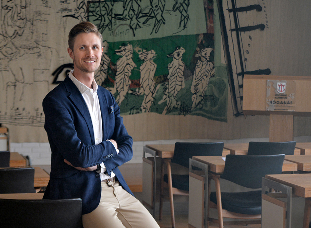 Man i blå kavaj sittande på ett bord.