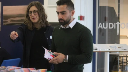 Två deltagare står vid ett informationsbord med broschyrer och material inför evenemanget.