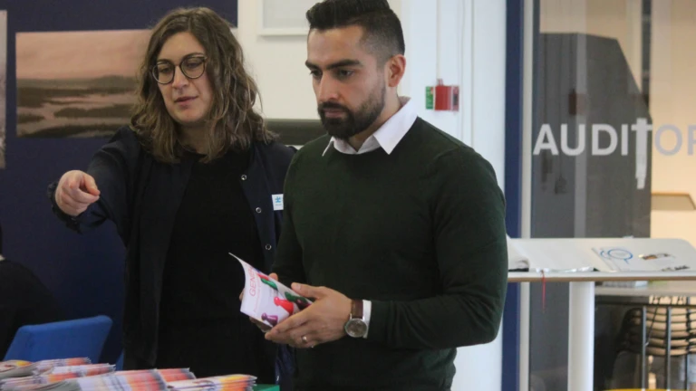 Två deltagare står vid ett informationsbord med broschyrer och material inför evenemanget.