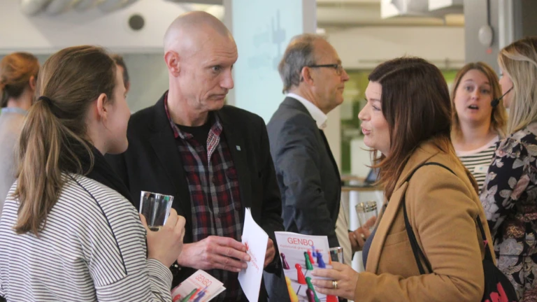 Gruppdiskussion mellan deltagare under pausen, där eventmaterialet diskuteras.