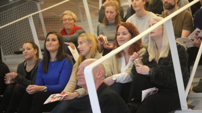 Flera deltagare sitter på trappan och följer en presentation eller föreläsning.