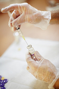 Fotografi av händer som arbetar med att fylla en spruta med vaccin.