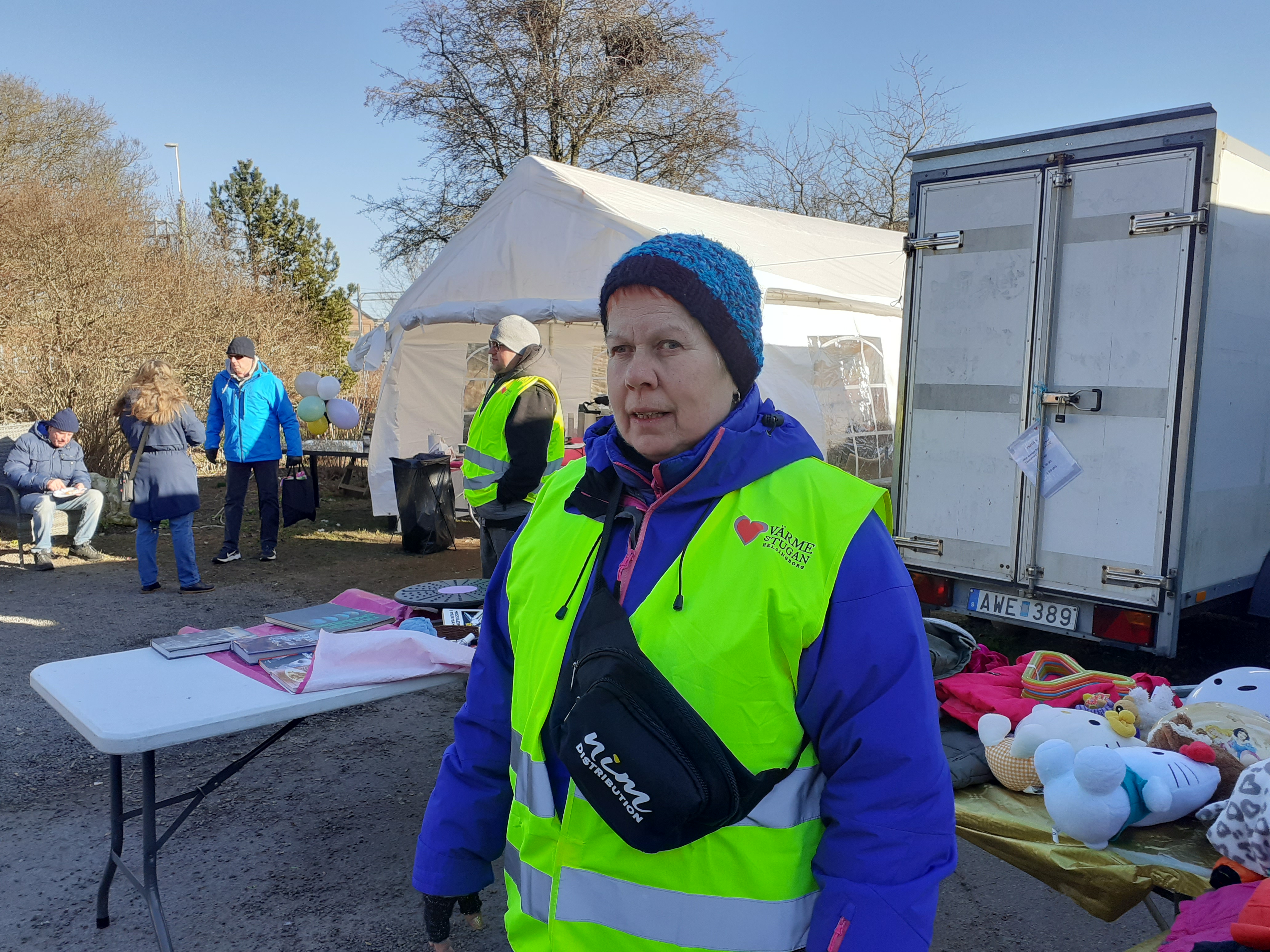 Volontär i gul väst står utanför Hemlösas hus.