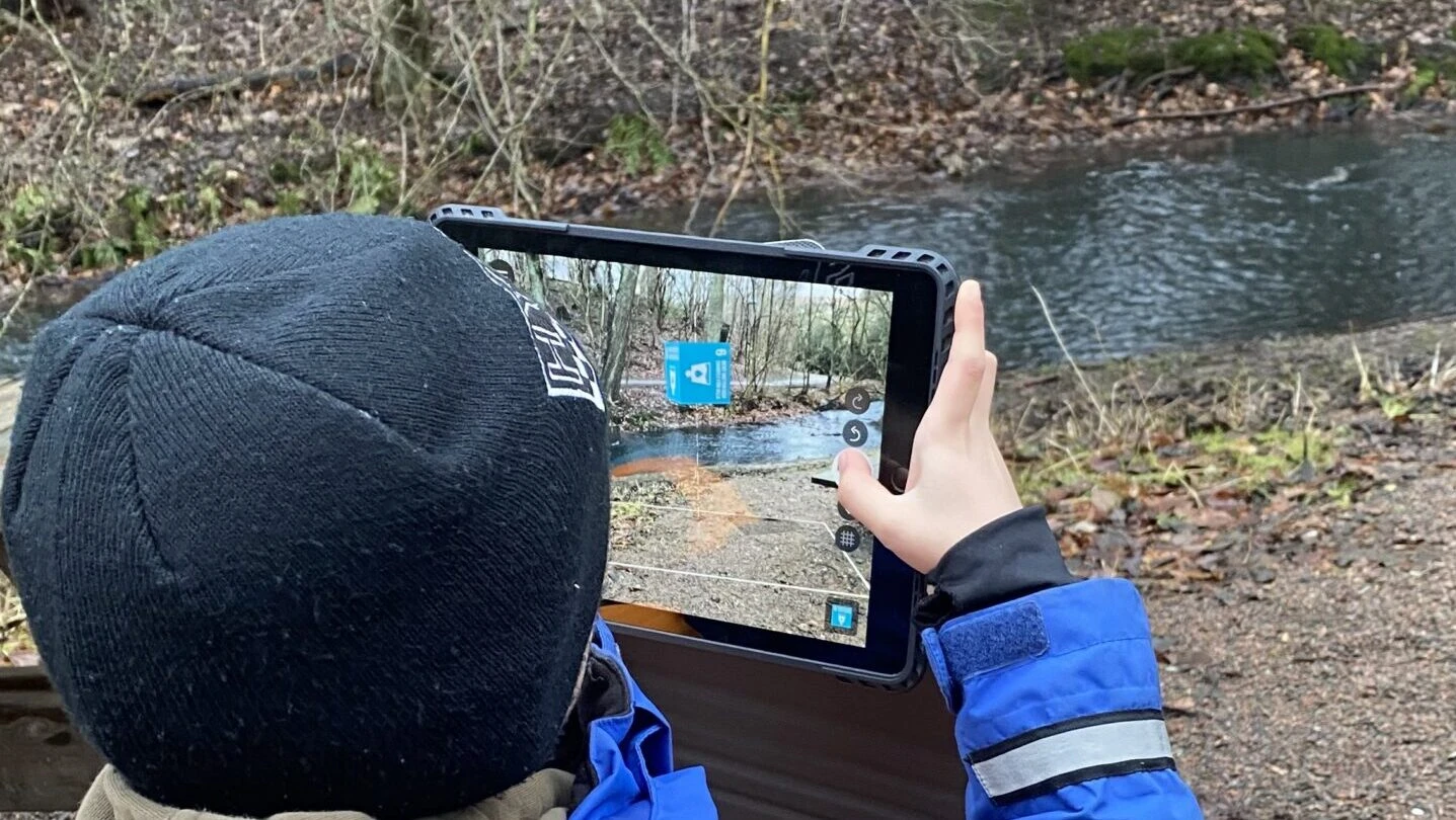 barn använder en ipad och utforskar en bäck