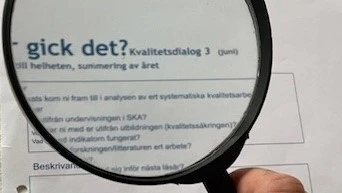 På bilden finns ett förstoringsglas som ligger över en text.