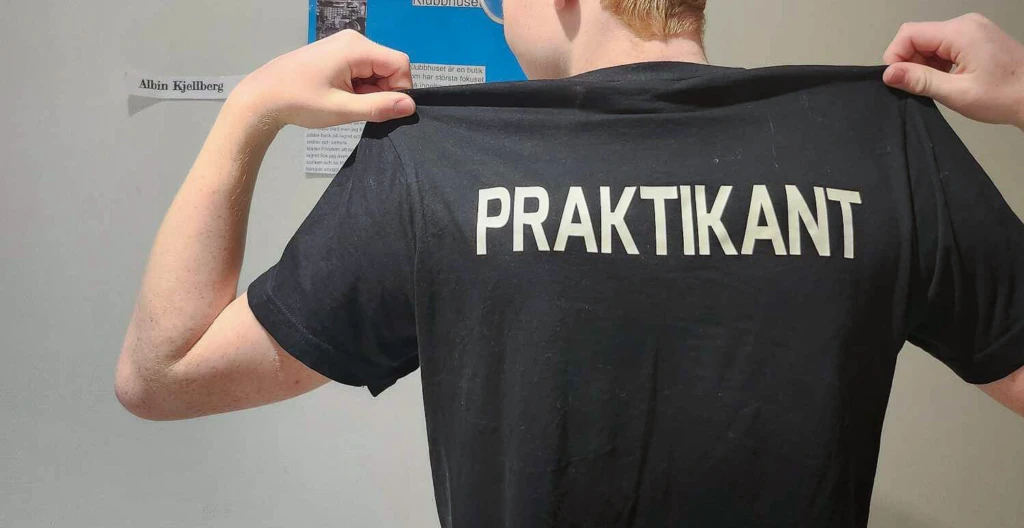 ungdom med texten "praktikant" tryckt på ryggen på sin t-shirt