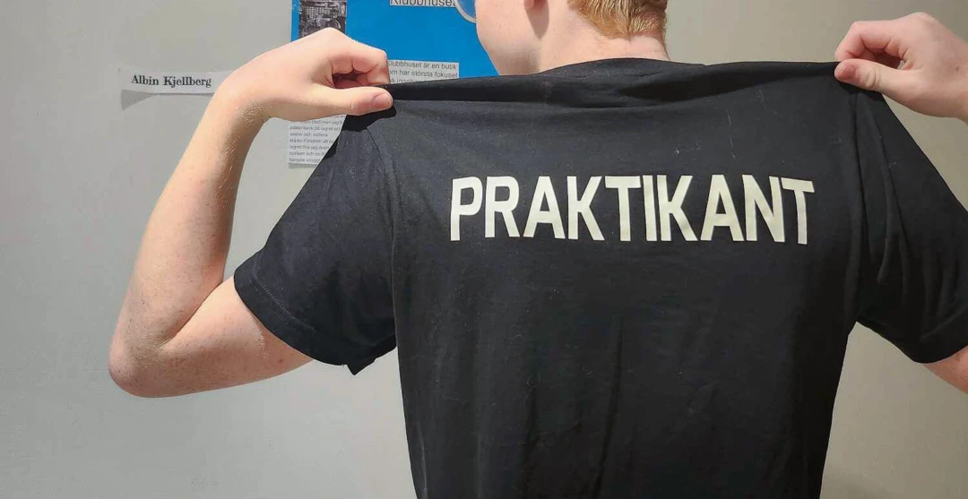 ungdom med texten "praktikant" tryckt på ryggen på sin t-shirt