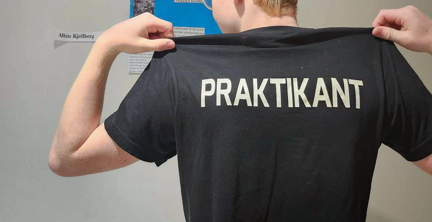 ungdom med texten "praktikant" tryckt på ryggen på sin t-shirt
