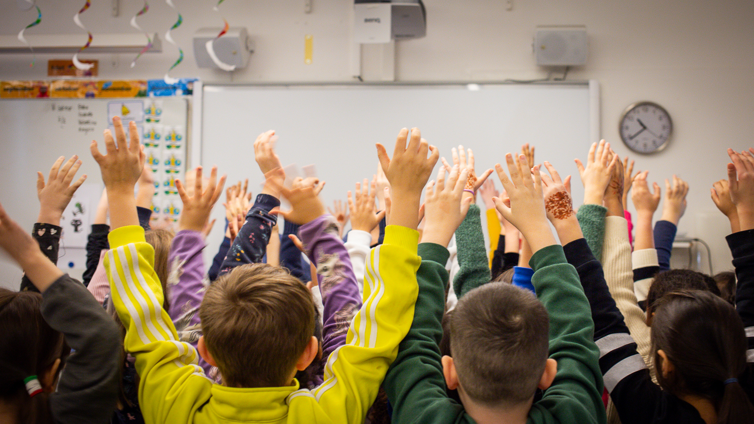 En skolklass med händerna i luften