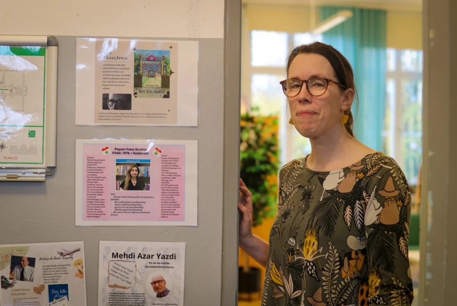 En kvinna står i en dörröppning, i bakgrunden syns ett skolbibliotek.