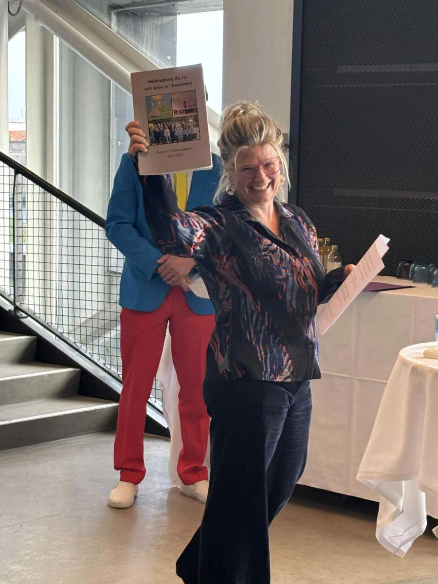 En kvinna ler och håller upp en bok