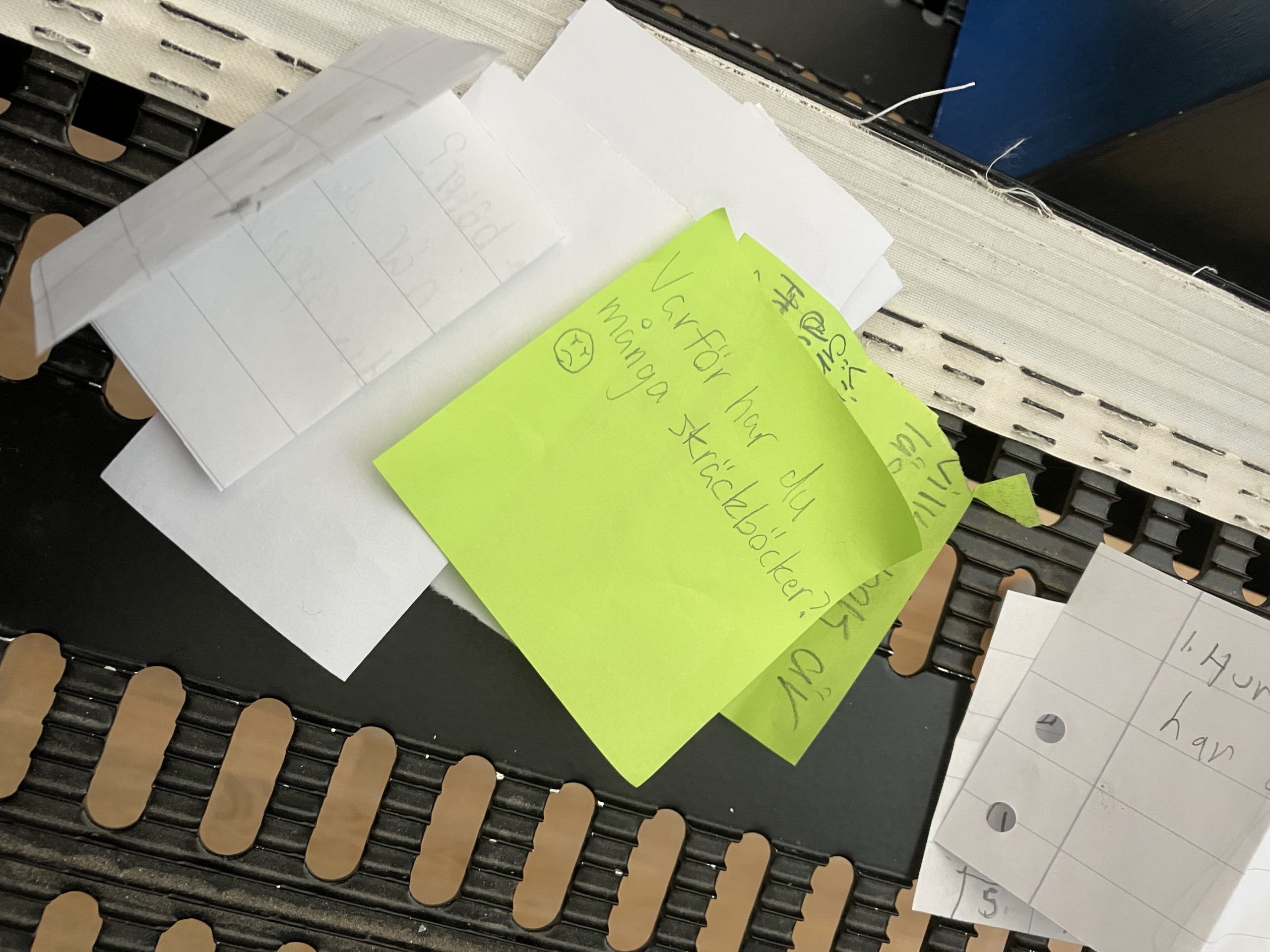 En hög med lappar där eleverna skrivit frågor till författaren för hand. I bild syns frågan: Varför har du många skräckböcker?