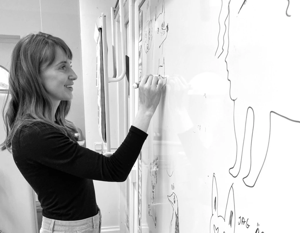 Författaren Ulrika ritar och skriver på en whiteboard tavla.