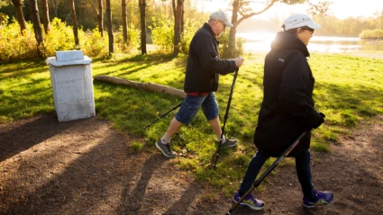 Man och kvinna på stavpromenad i naturområde i Helsingborg