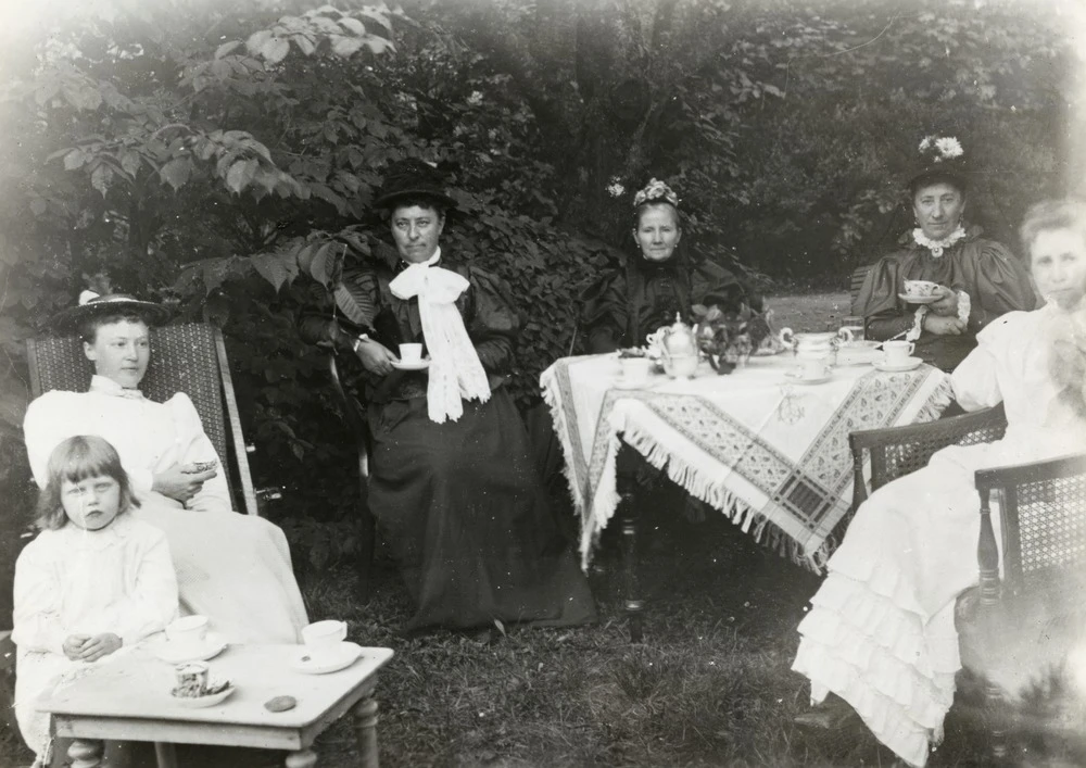 Svartvitt foto från 1894 som visar en samling kvinnor vid kaffebordet i trädgården.