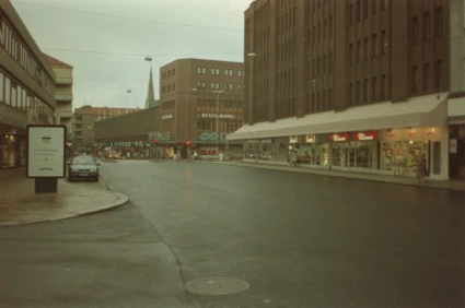 Gatuvy med Domus stora, bruna tegelbyggnad i bakgrunden.