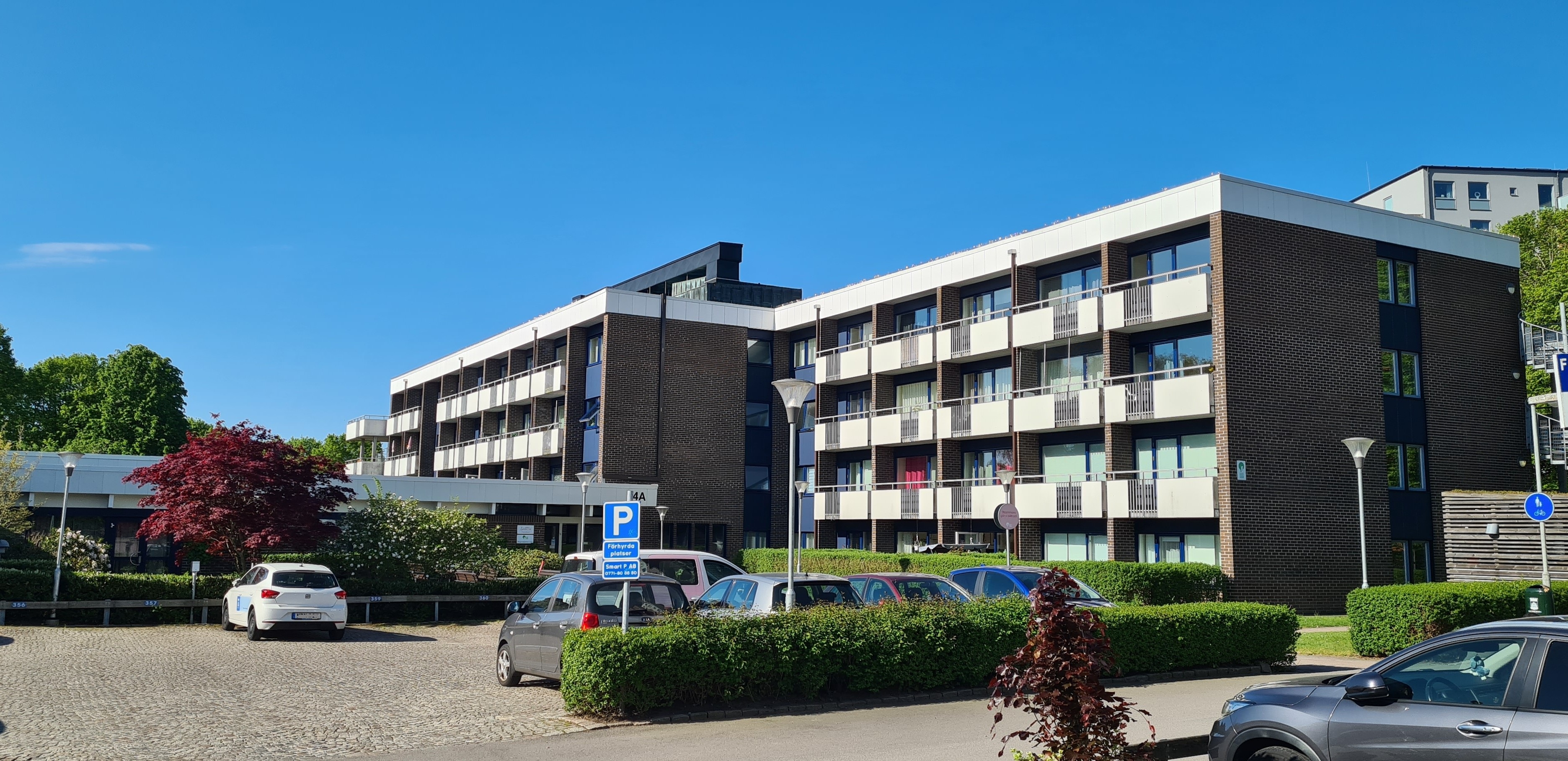 Våningsbyggnad i mörk tegel med vita detaljer. 