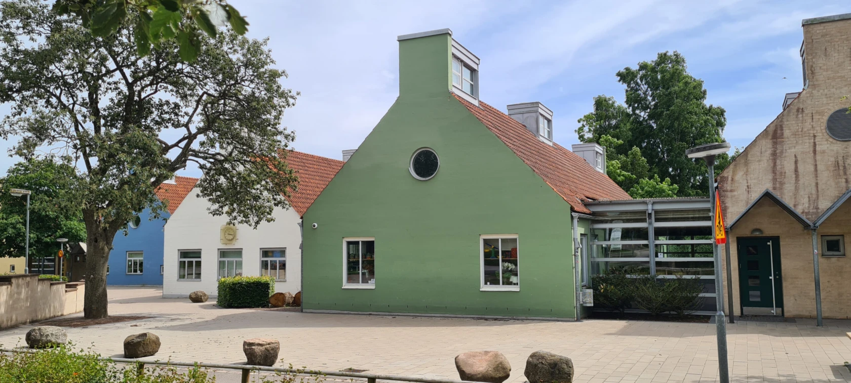 Färgfoto av husgavlar i milt grön, ljusblå och vit med lanterniner.