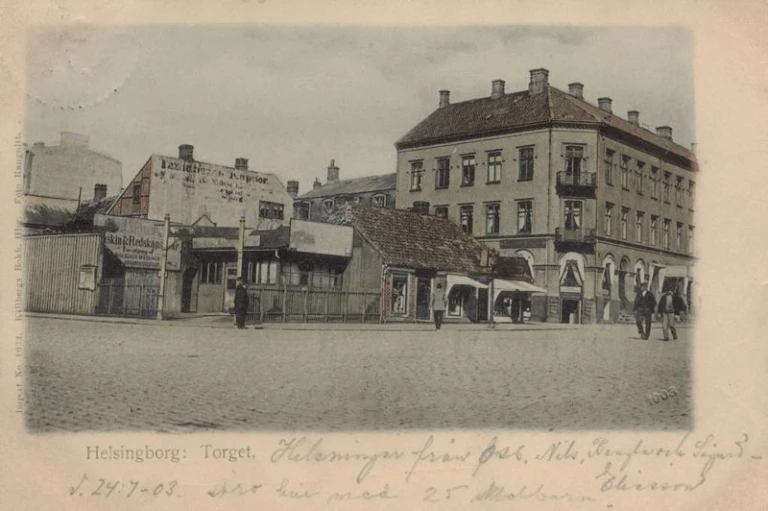 Svartvitt foto med trevåningsbyggna och en låg byggnad bredvid.