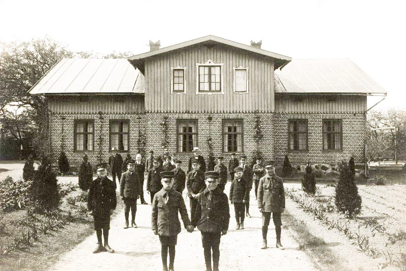 Barn runt förra sekeskiftet framför hus.