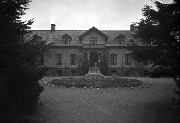 Svartvitt foto på tegelhus och gårdsplan.