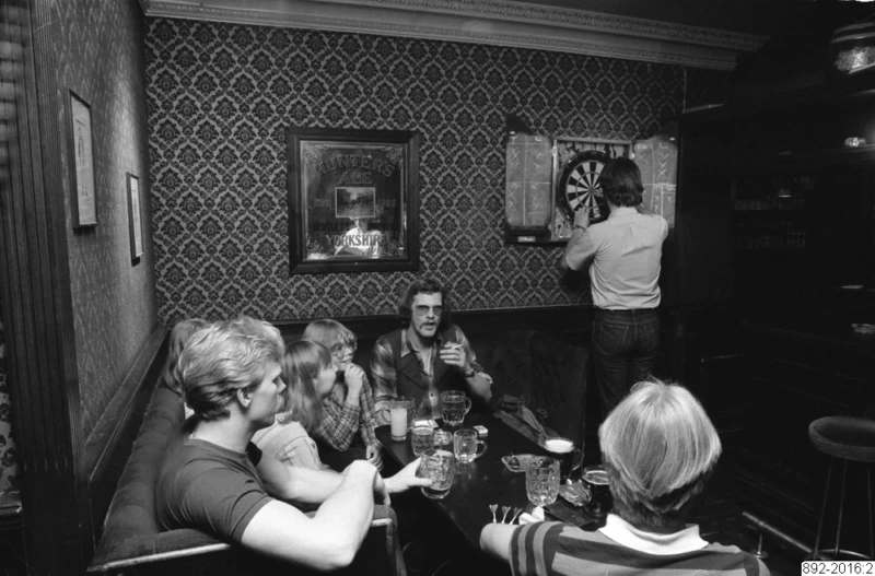 Pubmiljö med dart och folk som dricker öl.
