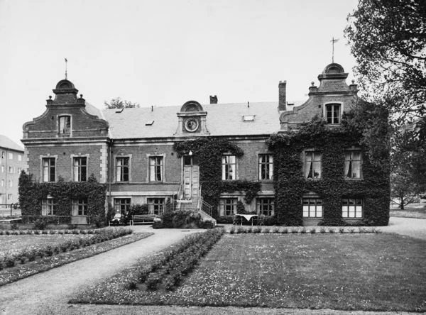 Svartvitt foto med byggnad i renässansstil i trädgård. 