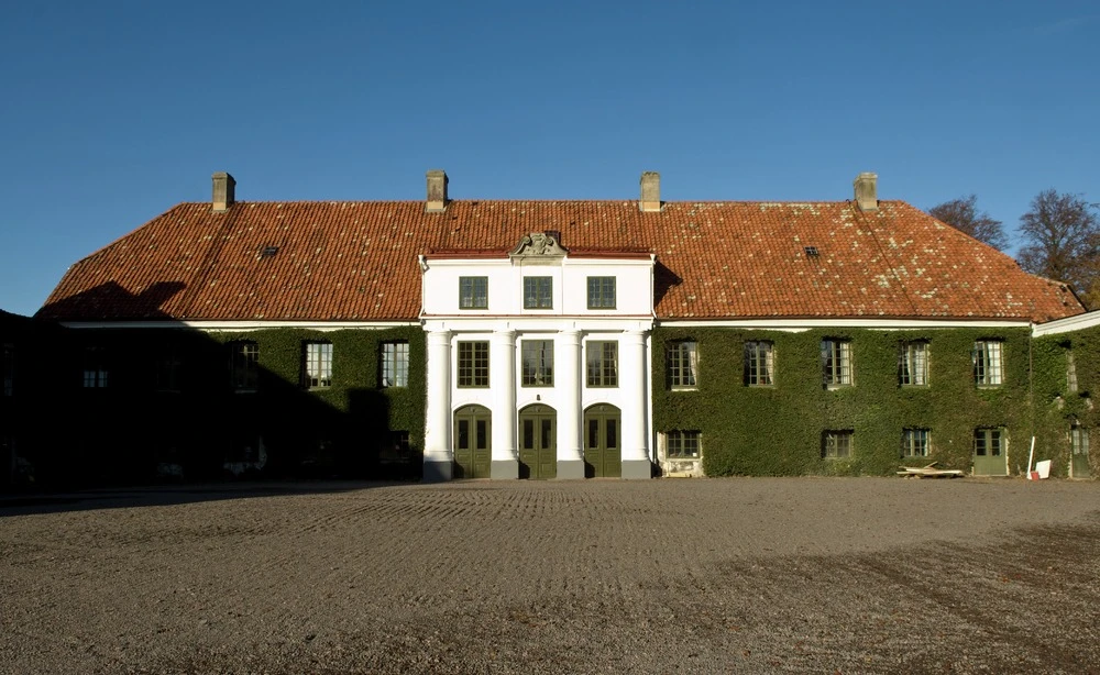 Huvudbyggnaden på Bälteberga säteri, entrén är inramad av pilastrar och fasaden täckt av murgröna.