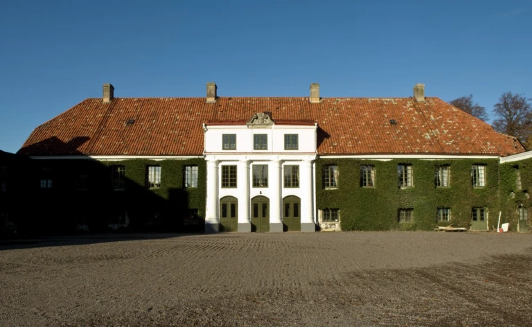 Huvudbyggnaden på Bälteberga säteri, entrén är inramad av pilastrar och fasaden täckt av murgröna.